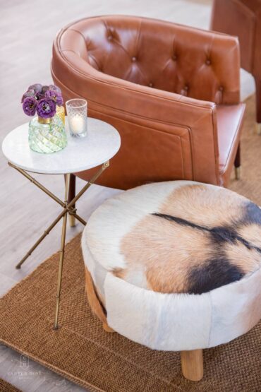Brown and white cowhide stool, marble bamboo accent table and henry arm chair