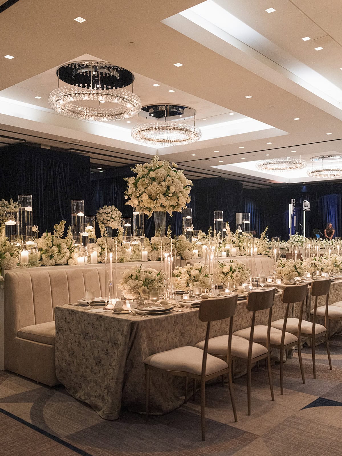 A long banquet table with white floral arrangements, candles, and elegant place settings.