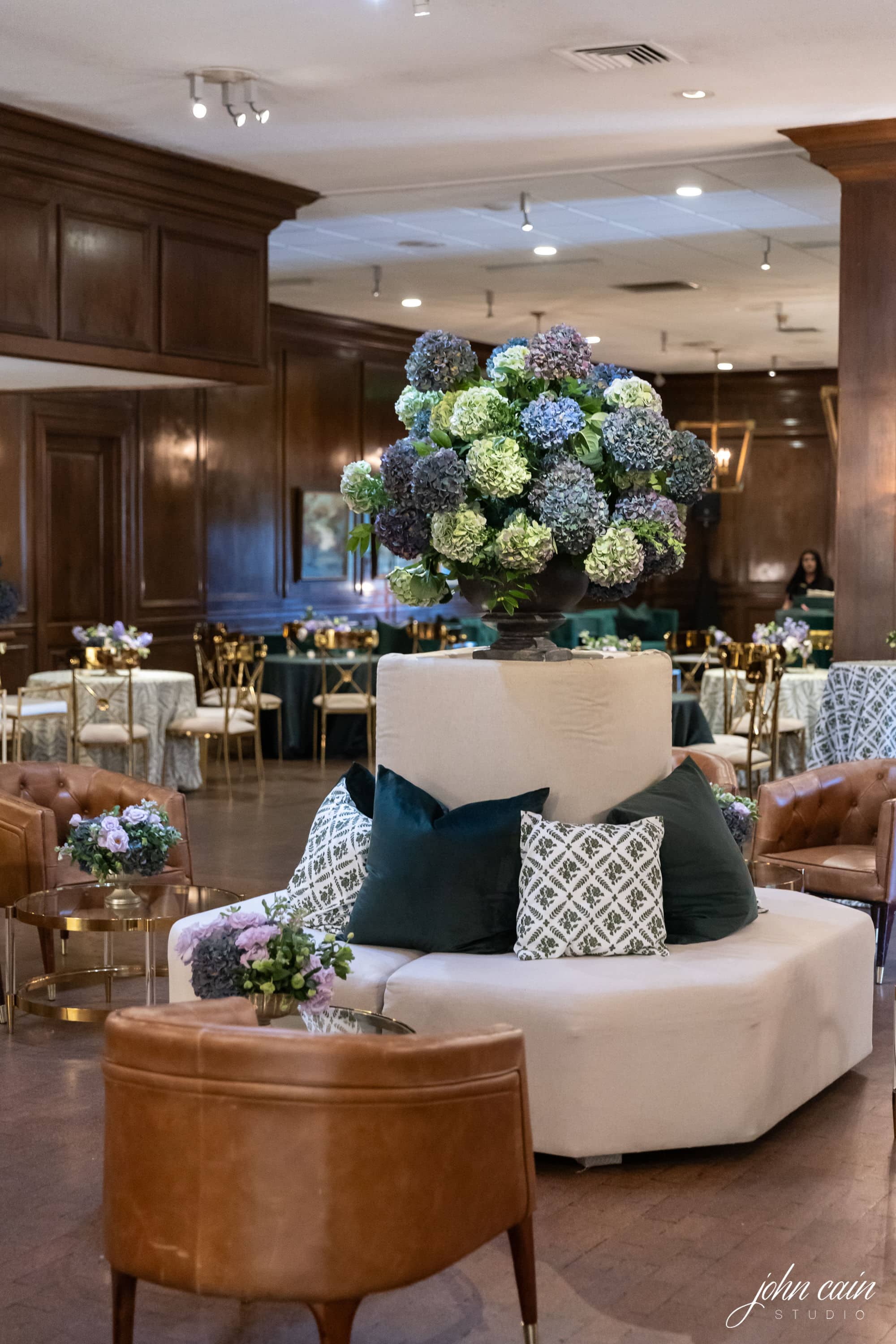 A large room with dark wood paneling, a beige curved sofa, and brown leather chairs.